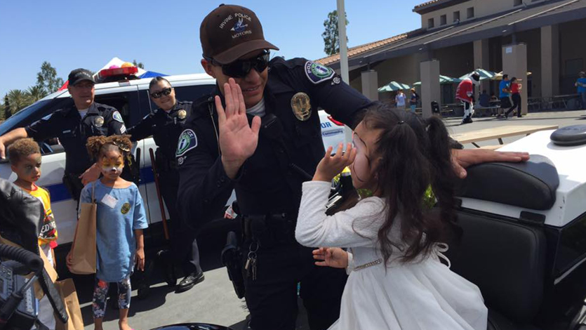 Irvine Police office high-fiving a young child