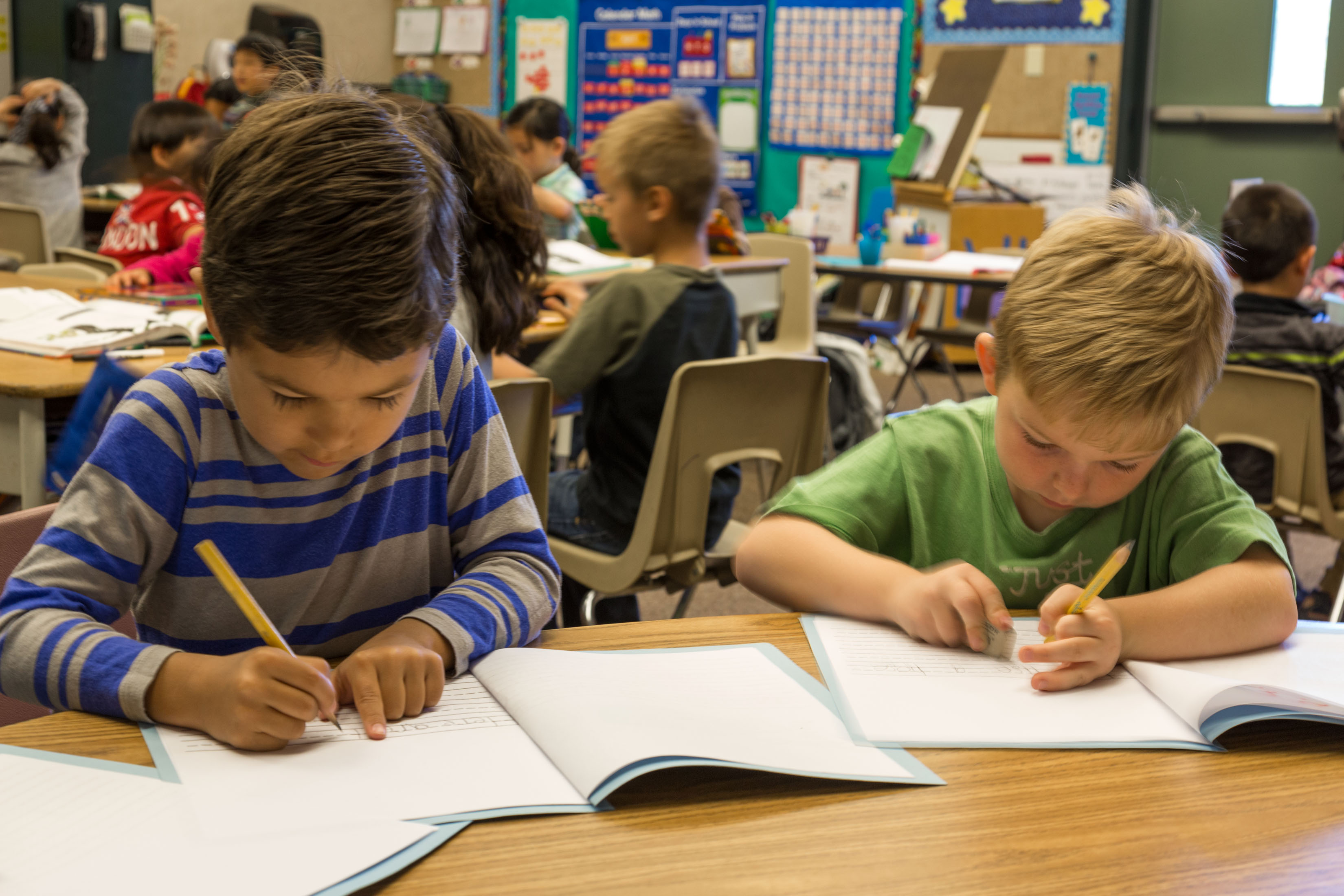 Two elementary school boys writing in workbooks